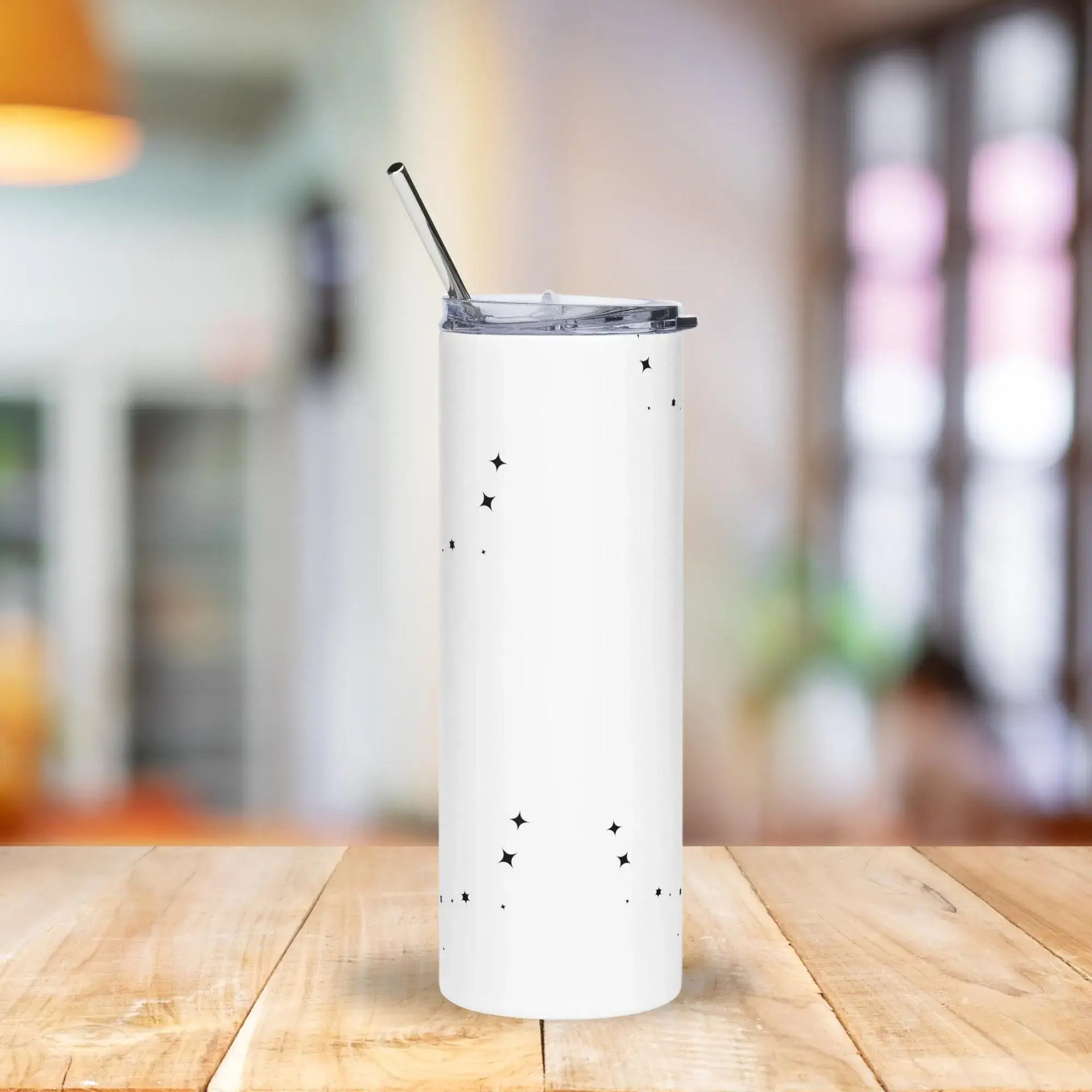 White tumbler with star patterns on a wooden table with a blurred indoor background