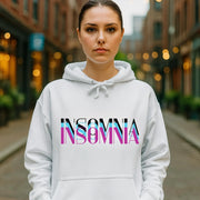 Person wearing a white hoodie with 'INSOMNIA' printed on it, standing on a city street.