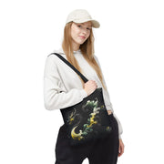 Person holding a black tote bag with dragon design on a white background