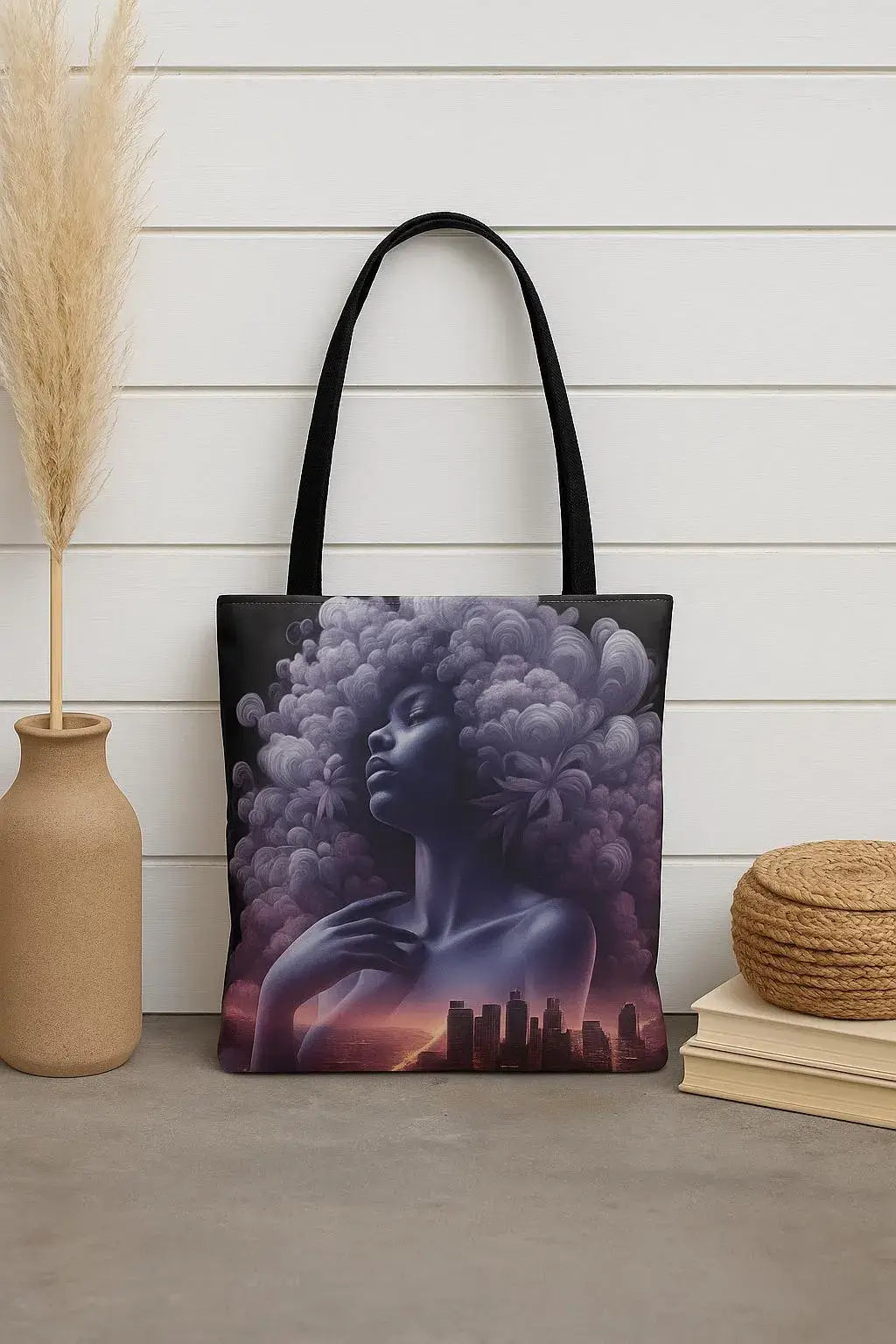 Tote bag with artistic design of a woman with an afro and cityscape, placed on a wooden floor.