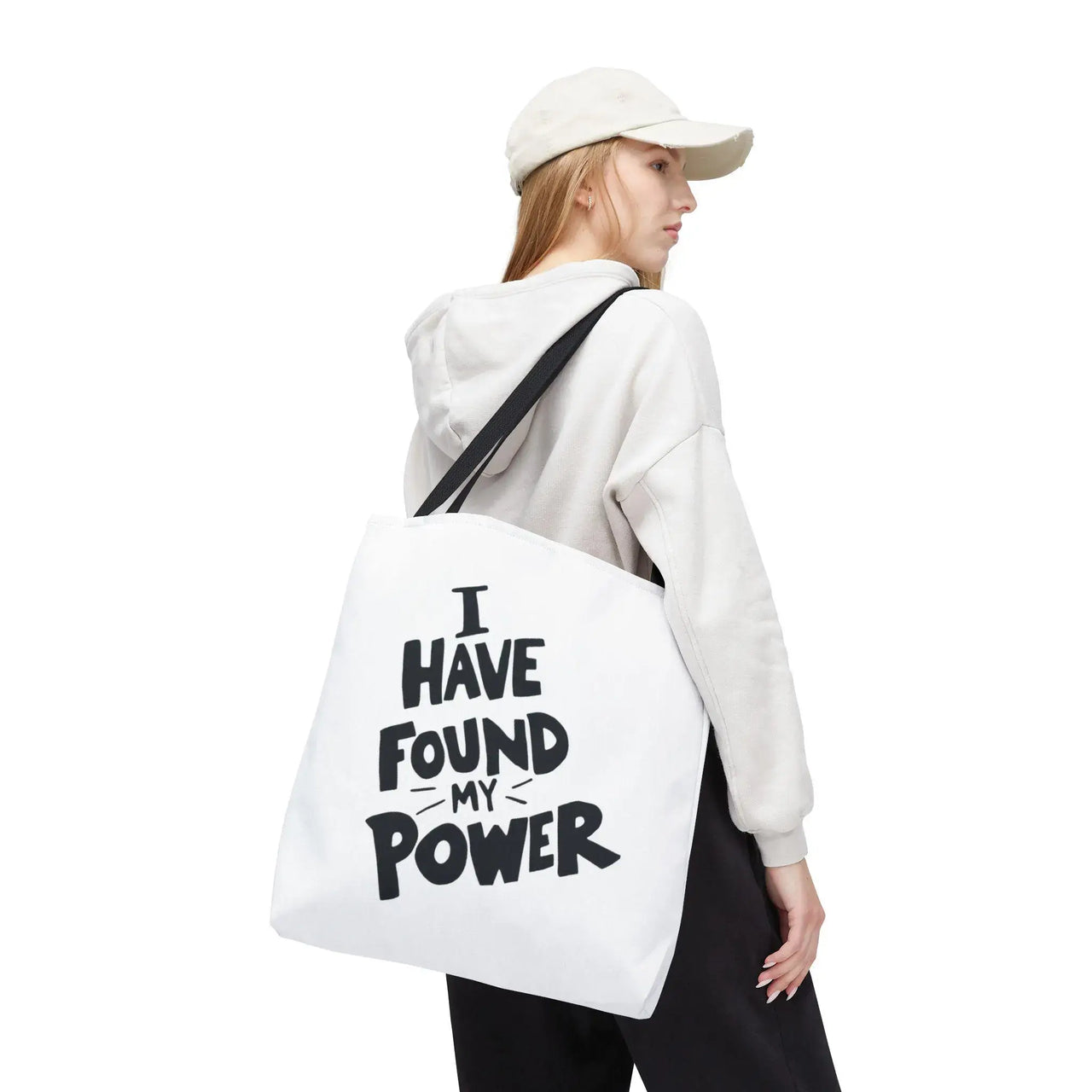 Person wearing a white hoodie with a tote bag that says 'I Have Found My Power' on a white background