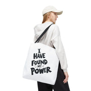 Person wearing a white hoodie with a tote bag that says 'I Have Found My Power' on a white background