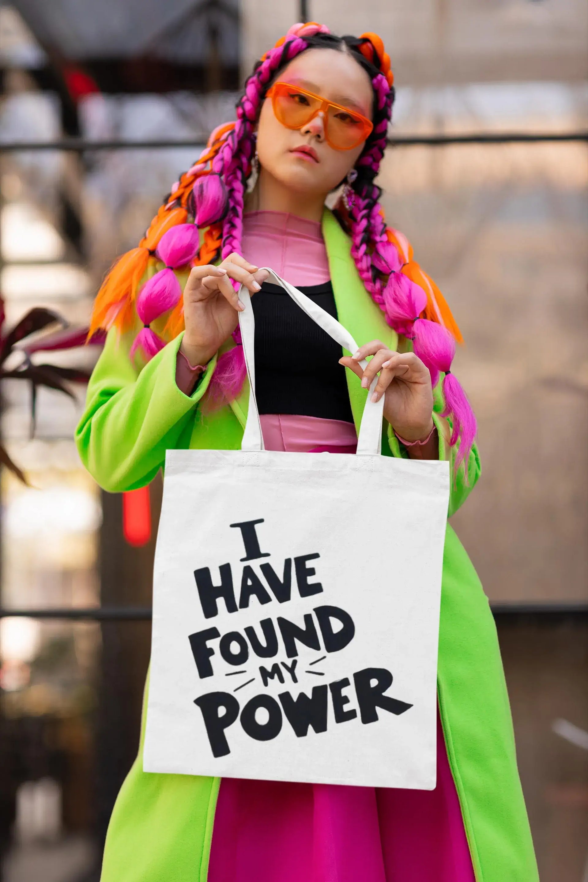 Person with colorful hair holding a tote bag with text, blurred background