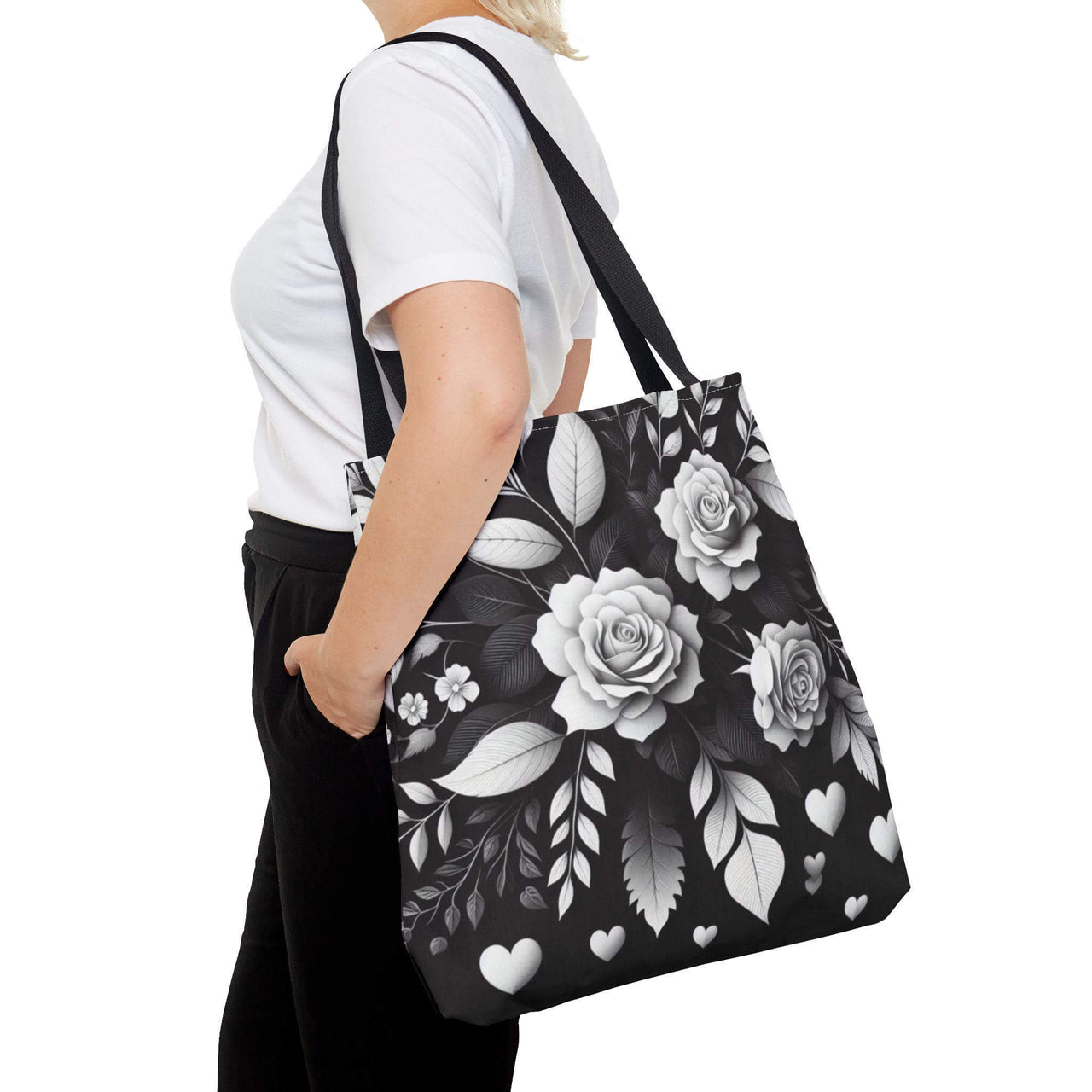 Person holding a black tote bag with white floral design on a white background