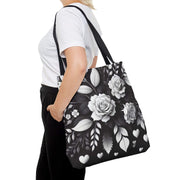 Person holding a black tote bag with white floral design on a white background