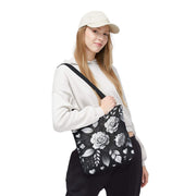 Woman holding a black bag with floral patterns on a white background