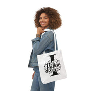 Woman holding a tote bag with 'I Believe' design on a white background