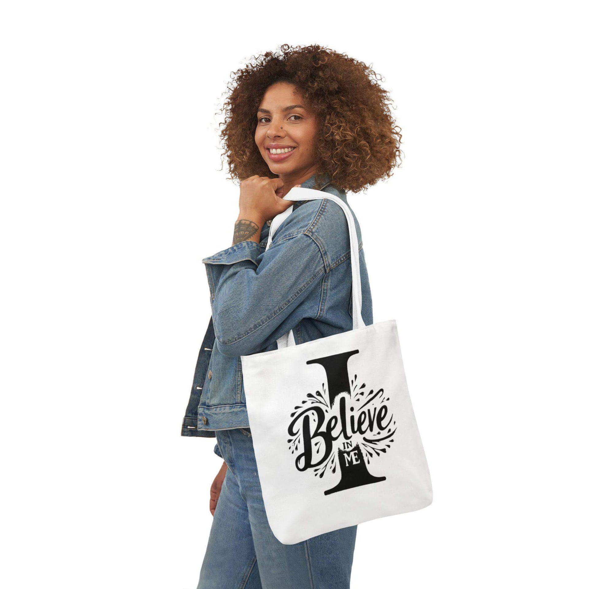 Woman holding a tote bag with 'I Believe' design on a white background