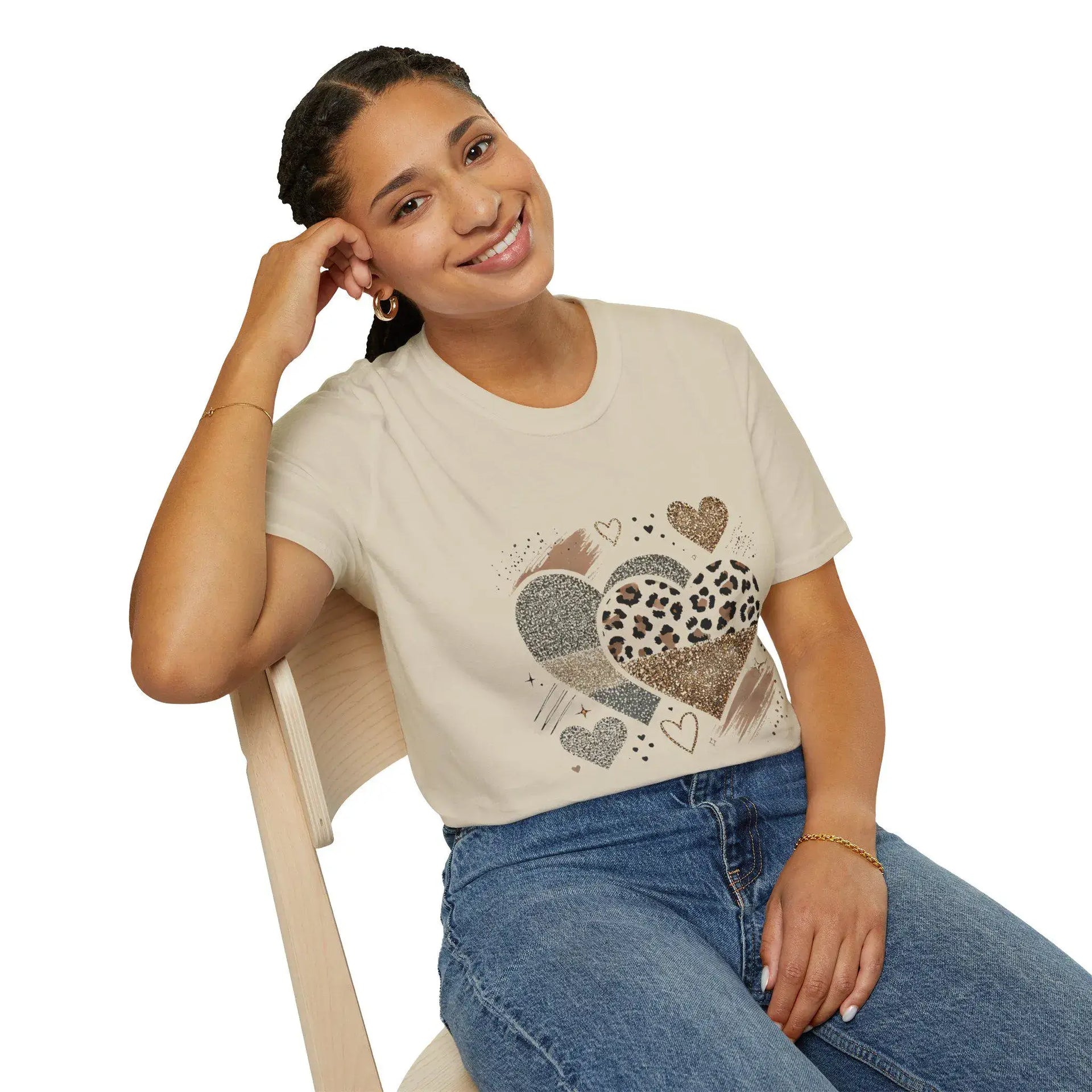 Woman wearing a beige t-shirt with heart designs and blue jeans, sitting on a white chair.