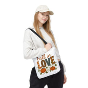 Person holding a tote bag with 'Fall in Love' text and pumpkin design on a white background