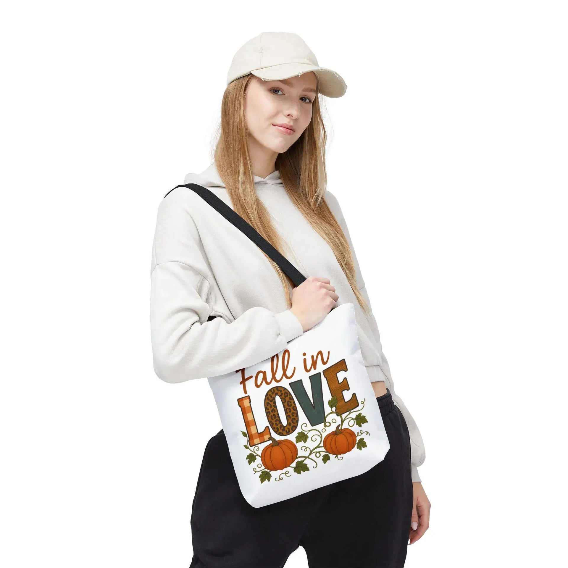Person holding a tote bag with 'Fall in Love' text and pumpkin design on a white background