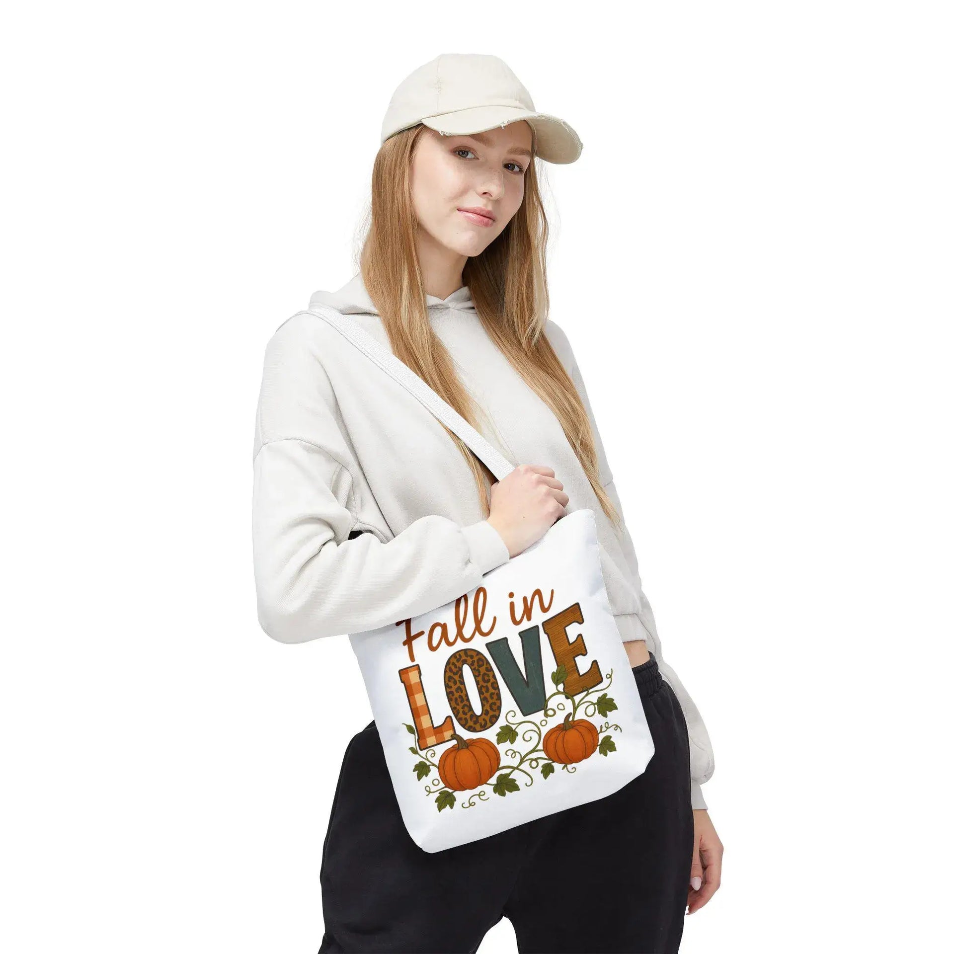 Person holding a tote bag with 'Fall in Love' text and pumpkins on a white background