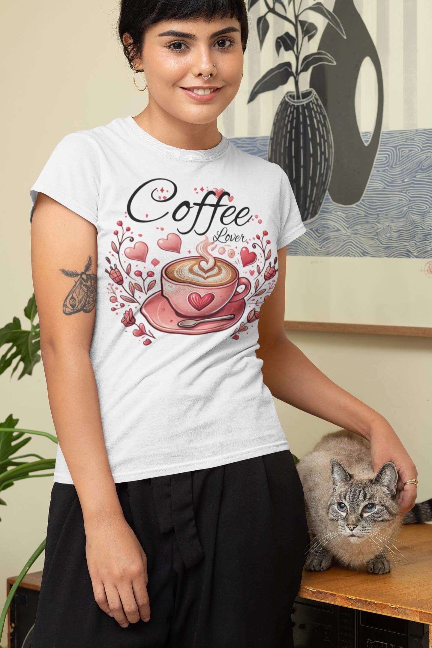 Person wearing a white t-shirt with a coffee-themed design, standing next to a cat.