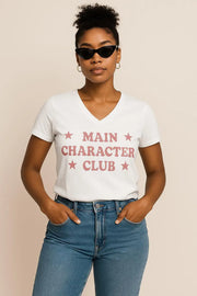 Woman wearing a white t-shirt with 'MAIN CHARACTER CLUB' text and blue jeans on a beige background