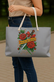 Gray tote bag with floral design and text held by a person outdoors