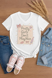 White t-shirt with 'Pretty Girls Don't Play Nice' graphic on a wooden surface with jeans and shoes.