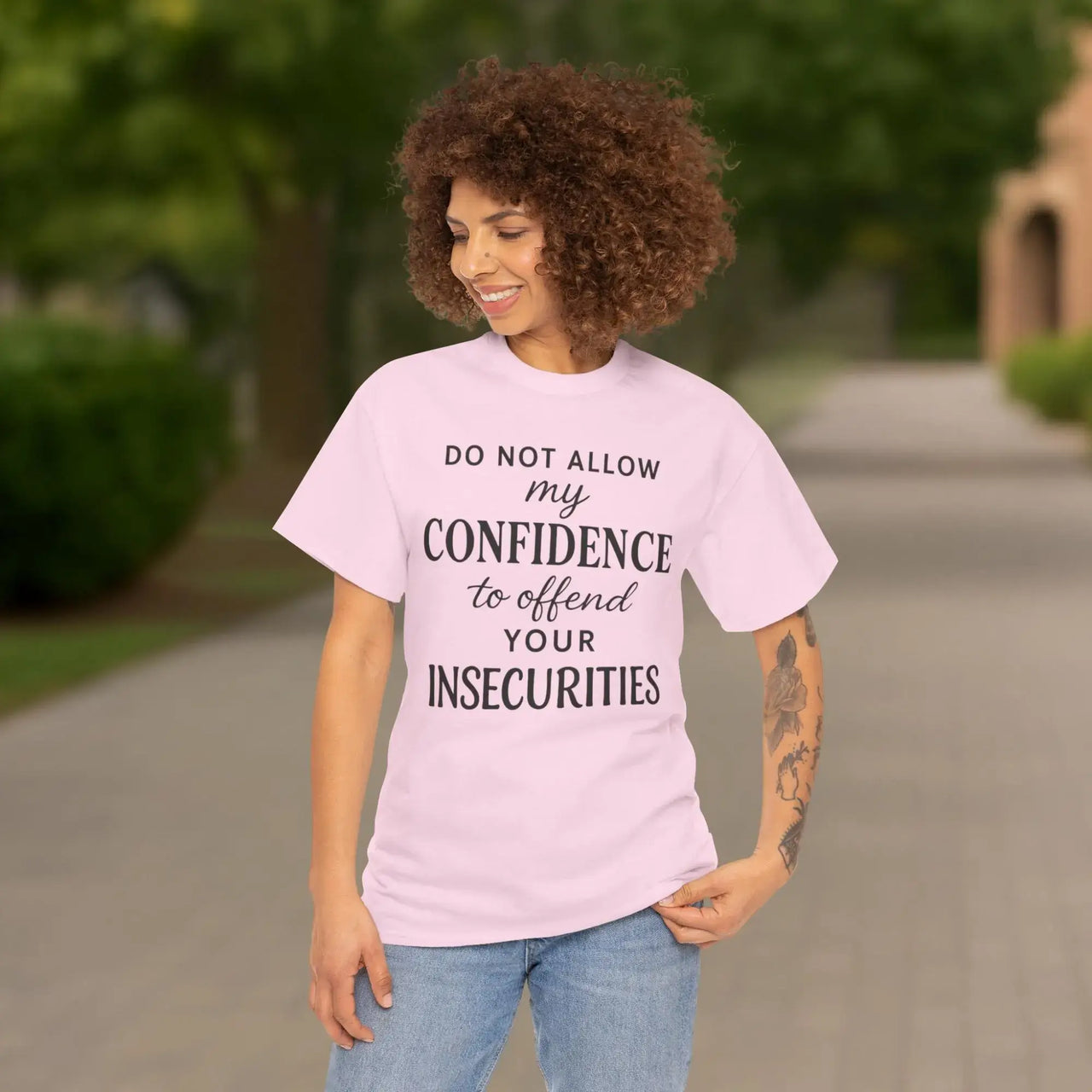 Woman wearing a pink t-shirt with a motivational quote outdoors.