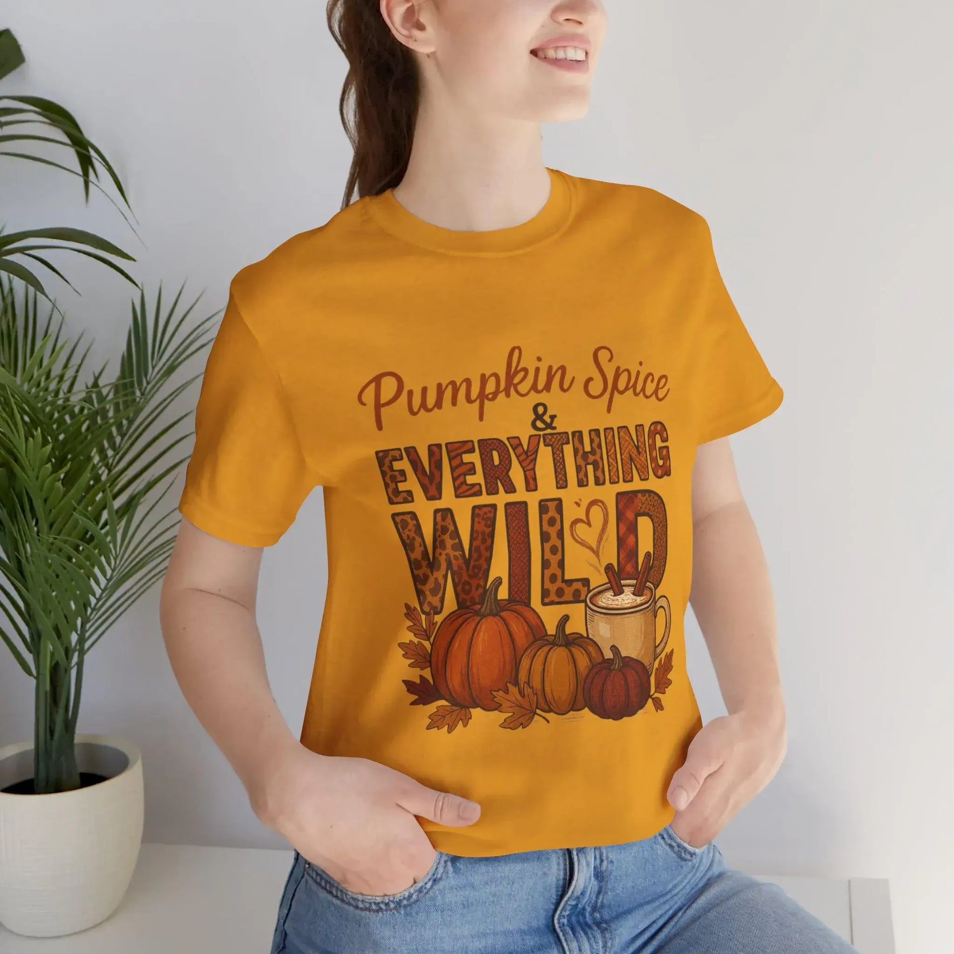 Person wearing a mustard yellow t-shirt with 'Pumpkin Spice & Everything Wild' text and graphics.