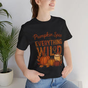 Person wearing a black t-shirt with 'Pumpkin Spice is EVERYTHING WILD' design, standing next to a plant.