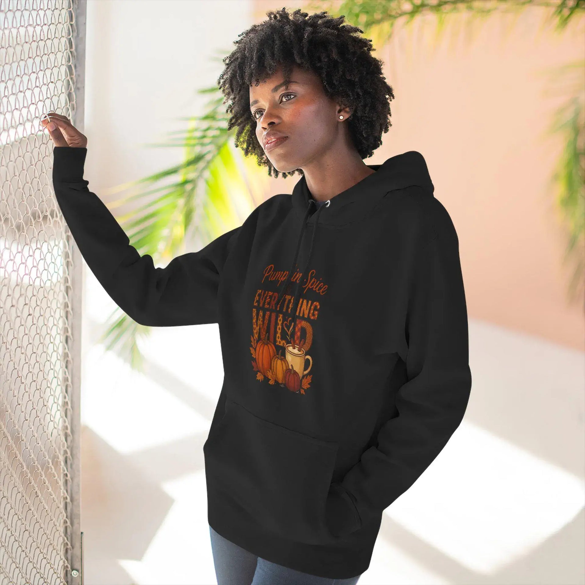 Person wearing a black hoodie with a graphic design, standing indoors with plants in the background.