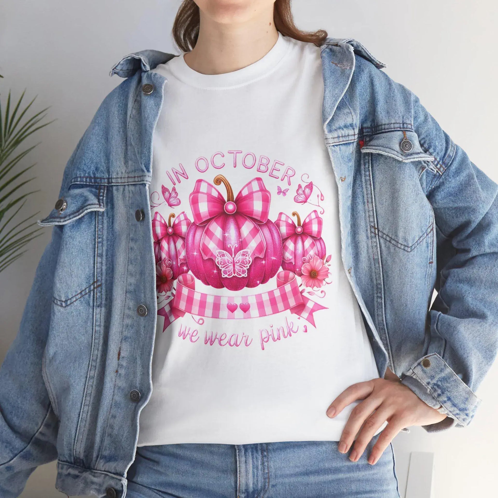 Person wearing a white t-shirt with a pink pumpkin design and text, paired with a denim jacket.